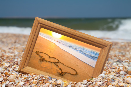 Photo frame on sand background, two hearts, love conceptの写真素材