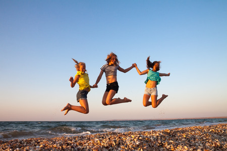 Concept of summer holidays and vacation - girls jumping on the beachの写真素材