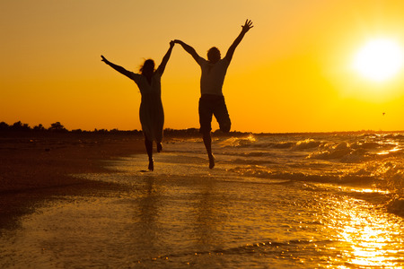 happy couple running on the beach on sunsetの写真素材