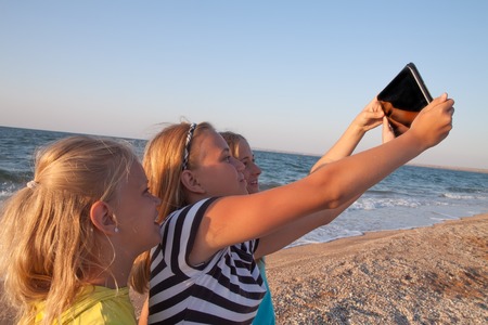 Group of girlfriends with tablet at the beach. Concept of friendship and fun in the summer with new trends and technology - Best friends enjoying the moment with modern tabletの写真素材