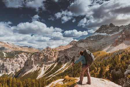 Female hiker with backpack standing on top in Dolomites mountainsの写真素材