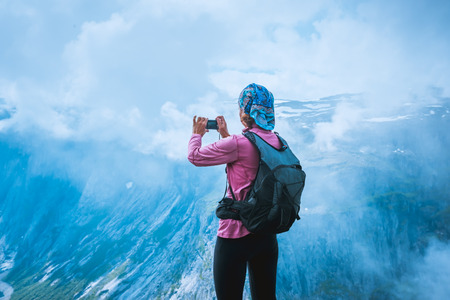 Nature photographer tourist with camera shoots while standing on top of the mountain. Beautiful Norway Natureの写真素材