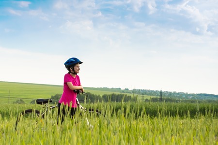 girl on a bicycle in summer rural landscapeの写真素材
