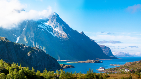 Scenic fjord on Lofoten islands with typical fishing hut and towering mountain peaksの写真素材
