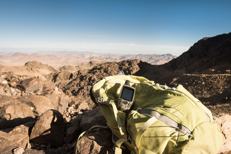 GPS navigator and backpack on mountain top in desertの写真素材