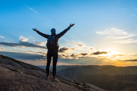 Woman successful hiking silhouette in mountains, motivation and inspiration in beautiful sunset. Female hiker with arms up outstretched on mountain top, inspirational landscapeの写真素材