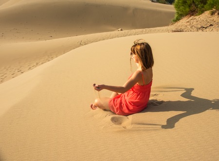 Girl in red relaxing in sandy desertの写真素材