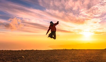 Happy man jumping for joy at sunset. Success, winner, happiness, ttavel concept.の写真素材