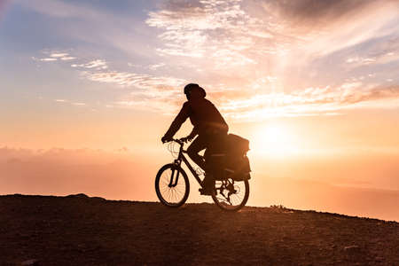 Mountain bicycle rider with backpack travels over sunrise backgroundの写真素材