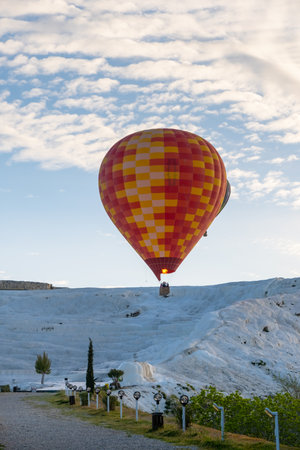 Hot air balloon flying over Travertine pools limestone terraces on a beautiful day. Pamukkale, Denizli, Turkey.の素材 [FY310200710930]