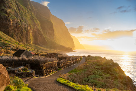 Volcanic rock cliffs Achadas da Cruz in backlit sunlight. Waves of the Atlantic Ocean. Beautiful sunset seascape of the resort island of Madeira, Portugalの写真素材
