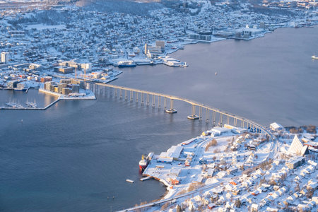 Aerial Panorama of norwegian city of Tromso in the winter. Snowy roofs, embankment near the port and fishing ships, Sunny winter day.の写真素材
