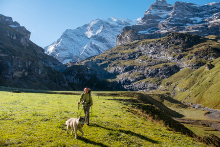 Woman with dog in Switzerland mountain valley Kiental, Berner Oberland Alps. Snow mountains, sunny weather, travel to Swiss, travelling with pet.の写真素材