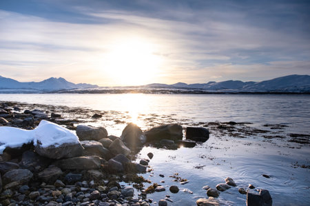 Snow covered Robukta coast of Norwegian fjord near Troms at Christmas time. A sunny winter day in Northern Norway above the Arctic Circleの写真素材