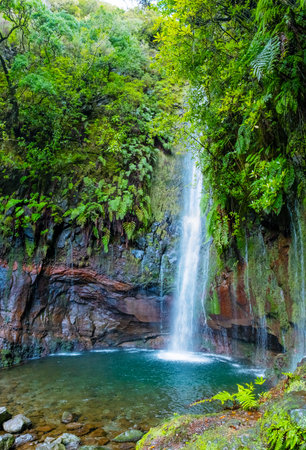 Majestic waterfall in Madeiras lush forest cascades down a rocky cliff, creating a serene stream below. The 25 Fontes or 25 Springs. Its a group of waterfalls located in Rabacal, Paul da Serraの写真素材