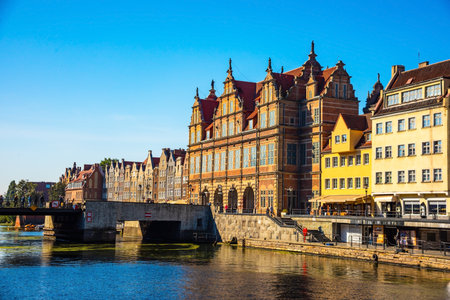 Scenic view of historic architecture and a bridge over a calm river in Gdansk, Poland. Bright day...