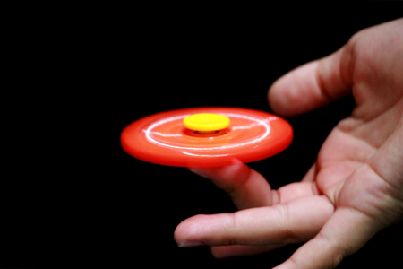 boy playing with a orange Hand Spinner toy on black background.の写真素材
