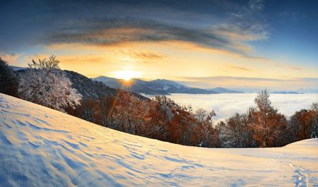 Sunrise in mountains in the autumn. The first snow and a morning fog.の写真素材