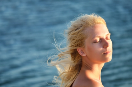 Beautiful girl with eyes closed against the seaの写真素材