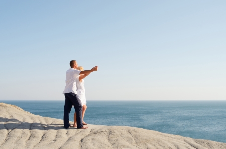 Young couple watching the sea holding handsの写真素材