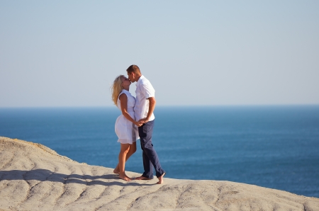 Young couple kissing on a rock by the seaの写真素材