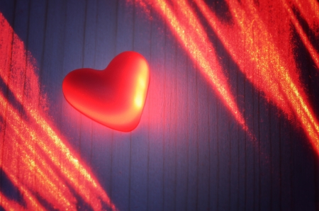 Sign of love from the polymer in the light of the laser on a wooden boardの写真素材