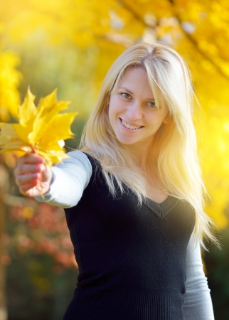 Blonde in a park holding a bouquet of autumn leavesの写真素材
