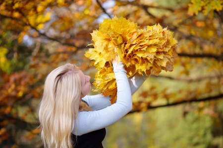 Blonde girl making a wreath of autumn leaves