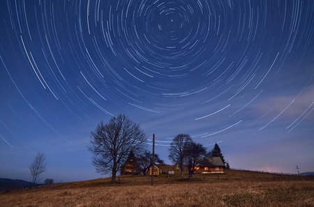 Night landscape with star tracks  Mountain village with wooden houses  Carpathians, Ukraine, Europeの写真素材