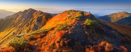 First rays of the sun on the mountain slopes  Panoramic landscape of the ridge with a footpathの写真素材