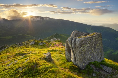 Summer landscape in the mountains with the sun hiding around the ridgeの写真素材