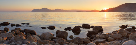 Landscape panorama at sunset  Sea shore with stones  A warm summer eveningの写真素材