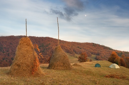 Autumn landscape. Haystack on the meadow. Tourist tent in a mountain village. Carpathians, Ukraine, Europeの写真素材