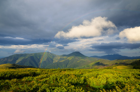 Summer landscape with a rainbow in the mountains. Sunshine after the rain. Beauty in natureの写真素材