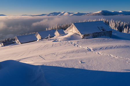 Winter landscape. Wooden houses in the snow. Mountain village of shepherds. Sunny weather in the morning. Carpathians, Ukraine, Europeの写真素材