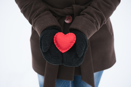 Girl holding a red decorative heart in his handsの写真素材
