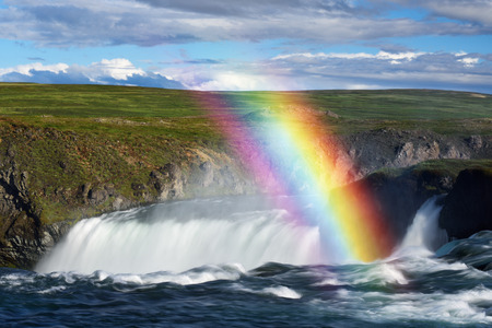 Summer landscape in Iceland, Europe. Godafoss waterfall and rainbow. Sunny day with beautiful cloudsの写真素材