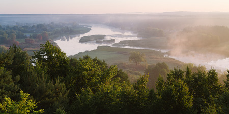 Summer landscape with the beautiful river and morning fog. Deciduous forest on a hill. Ros river, Ukraine, Europeの写真素材