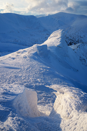Winter landscape with rocks in the mountains. Beautiful snow and neve on the stones. The light of the setting sun. Carpathians, Ukraine, Europeの写真素材