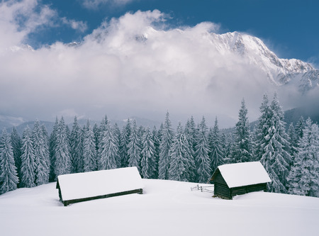 Winter landscape with wooden houses. Cloudy weather in the mountains. Collage of two frames. Color toningの写真素材