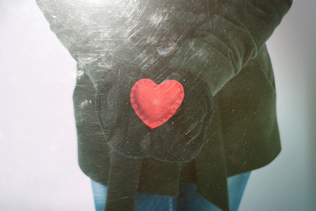 Girl holding a red decorative heart in his hands. Color toning. Effect of old photos from scuffs and scratchesの写真素材