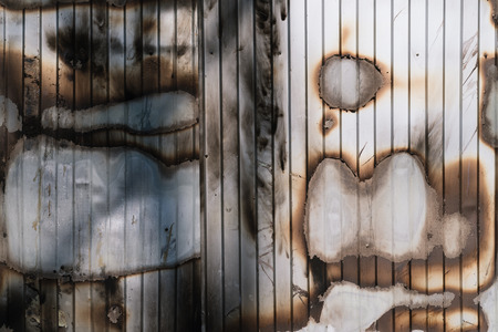 Charred wall of metal profile after a fire. Abstract background with stains for designの写真素材