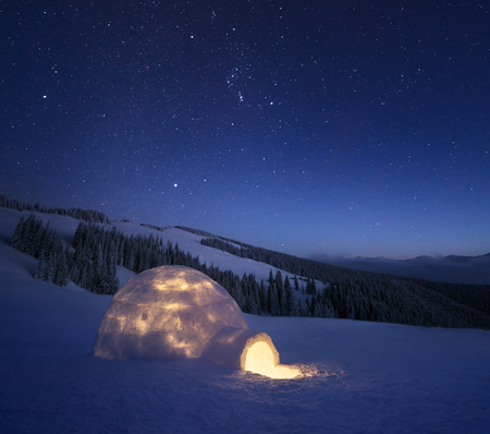 Night landscape with a snow igloo with light. Extreme house. Winter in the mountains. Sky with the...
