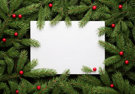 Christmas card background. Paper notice sheet with copy space for text.  Decorative frame of fir branches and holly berries. Flat lay, top viewの写真素材