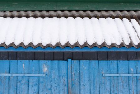 Winter background for design. Abstract geometric fragment of old architecture. Blue gates and slate roof in the snowの写真素材
