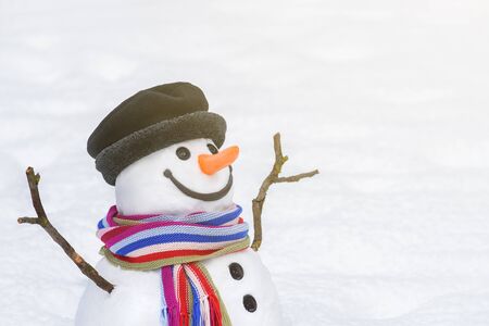 Christmas (New Year) card with a smiling snowman in a city park. White copy space to insert a greeting or festive textの写真素材