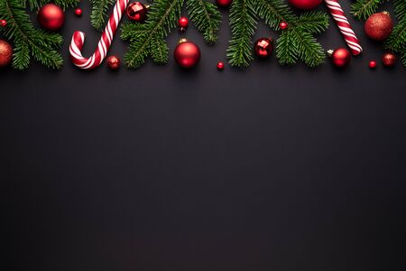 Black christmas background. Festive border of fir branches, Christmas balls and candy canesの写真素材