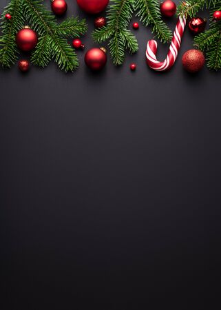 Black Christmas or New Year background. Decorative border of fir branches, red Christmas balls and Candy canes. Copy space for textの写真素材