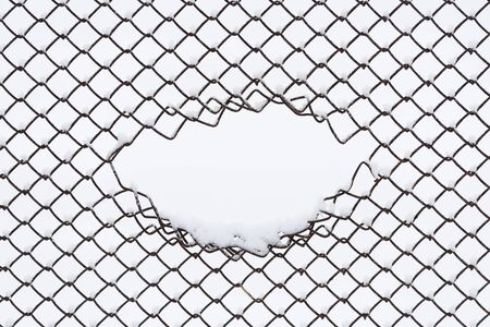 Abstract winter background with copy space. Geometric pattern of a wire fence in the snow