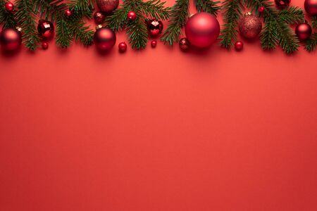 Red background with Christmas balls and fir branches. Merry Christmas or New Year decoration with copy spaceの写真素材